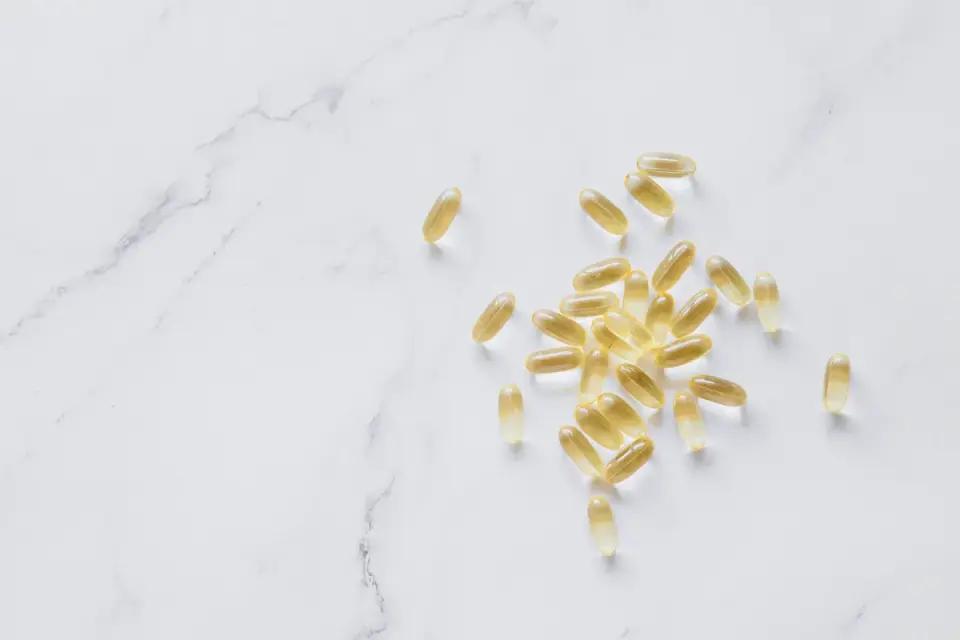 Fish oil softgel supplements next to a dog&#x27;s food bowl