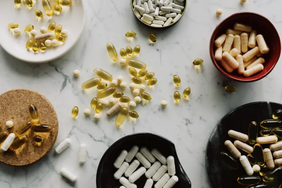 Soft-gel supplement capsules next to a dog&#x27;s food bowl on a kitchen counter